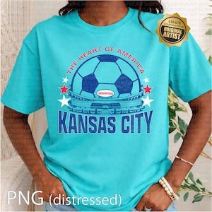 Puede incluir: Camiseta turquesa con un dise&ntilde;o gr&aacute;fico desgastado. El dise&ntilde;o incluye un bal&oacute;n de f&uacute;tbol, las palabras "THE HEART OF AMERICA" y "KANSAS CITY", y el estadio Arrowhead. Cuello redondo, mangas cortas.