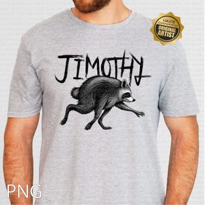 May include: A heather gray short-sleeve t-shirt featuring a black ink-style illustration of a raccoon in a running pose. Above the raccoon, the text JIMOTHY is printed in a stylized, jagged black font. A gold star-shaped badge is in the top right.