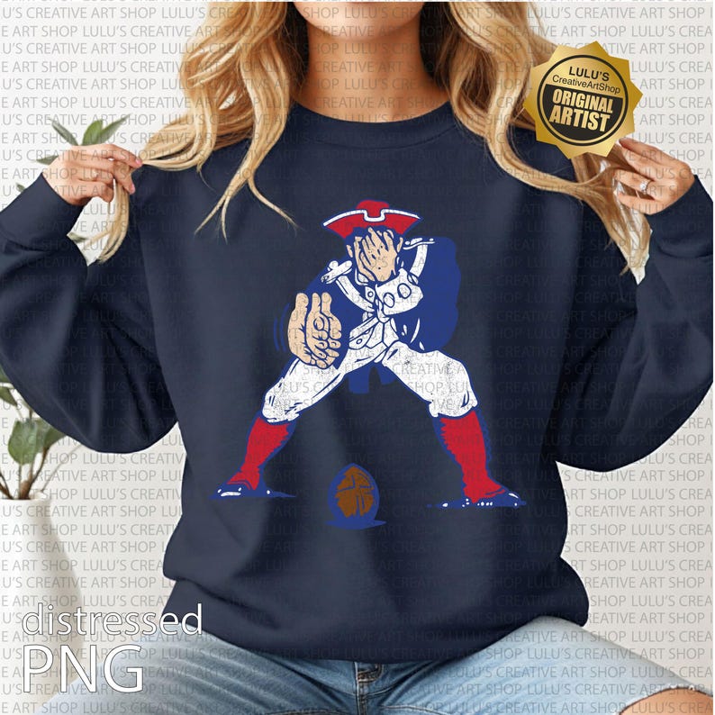 Op de afbeelding: Marineblauwe sweatshirt met een vervaagde afbeelding van een koloniale figuur in rood, wit en blauw, met een voetbal. Het ontwerp bevat de tekst "Lulu's Creative Art Shop" en "Original Artist".
