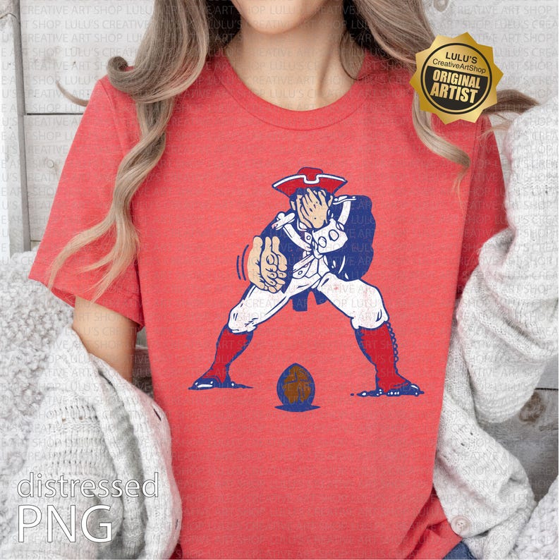 Op de afbeelding: Rood T-shirt met een patriottisch ontwerp van een koloniale figuur die een voetbal gooit. De figuur is in blauw, wit en rood. Een voetbal ligt aan zijn voeten. Het shirt heeft onderaan de tekst "distressed PNG".