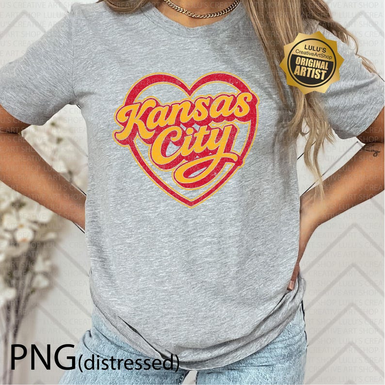 May include: A heather gray t-shirt featuring a red heart with the words "Kansas City" in yellow script. The shirt has short sleeves and a crew neck. The text "PNG (distressed)" is at the bottom.