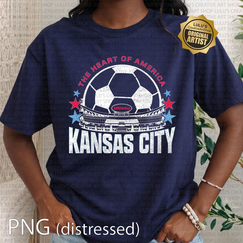Puede incluir: Camiseta azul marino con un dise&ntilde;o de bal&oacute;n de f&uacute;tbol, el texto "THE HEART OF AMERICA" y "KANSAS CITY". El dise&ntilde;o incluye estrellas rojas y azules y una imagen de un estadio. Efecto PNG desgastado.