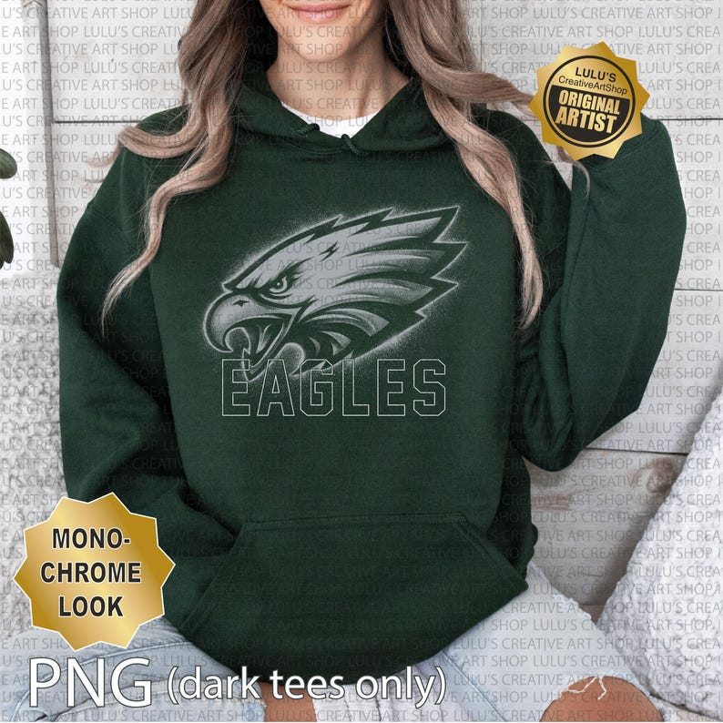 May include: A dark green hoodie with a monochrome eagle head design and the word "EAGLES" in white. The hoodie has a hood with a drawstring and a front pocket. The image also includes text that says "MONOCHROME LOOK" and "PNG (dark tees only)".