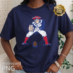 Op de afbeelding: Marineblauw T-shirt met een verweerde afbeelding van een koloniale soldaat in rood, wit en blauw, met een voetbal. Het shirt heeft de tekst "distressed PNG" en een gouden "ORIGINAL ARTIST" zegel.
