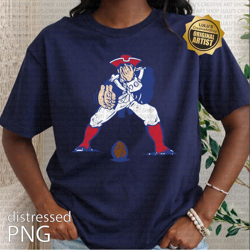 Op de afbeelding: Marineblauw T-shirt met een verweerde afbeelding van een koloniale soldaat in rood, wit en blauw, met een voetbal. Het shirt heeft de tekst "distressed PNG" en een gouden "ORIGINAL ARTIST" zegel.