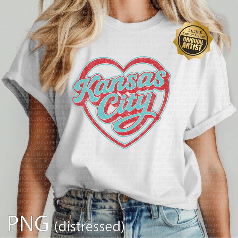 May include: White t-shirt featuring a distressed design with the words "Kansas City" in a heart-shaped graphic. The text is in a retro style, with red and turquoise colors. The shirt has rolled-up sleeves.