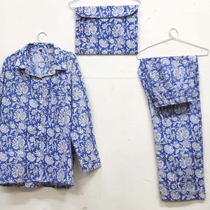 May include: A blue and white floral print pajama set with a long-sleeved shirt and pants. The set is hanging on hangers.