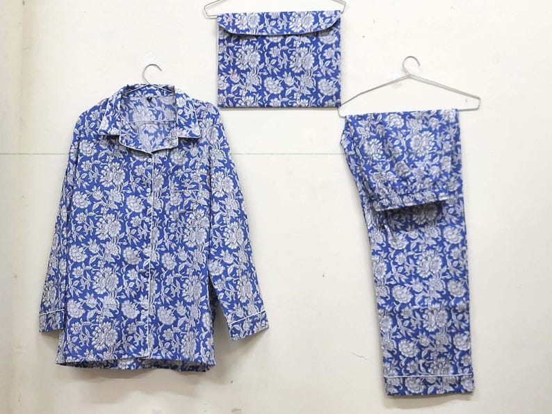 May include: A blue and white floral print pajama set with a long-sleeved shirt and pants. The set is hanging on hangers.