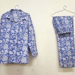 May include: A blue and white floral print pajama set with long sleeves and pants. The set is made of cotton and has a button-up top.