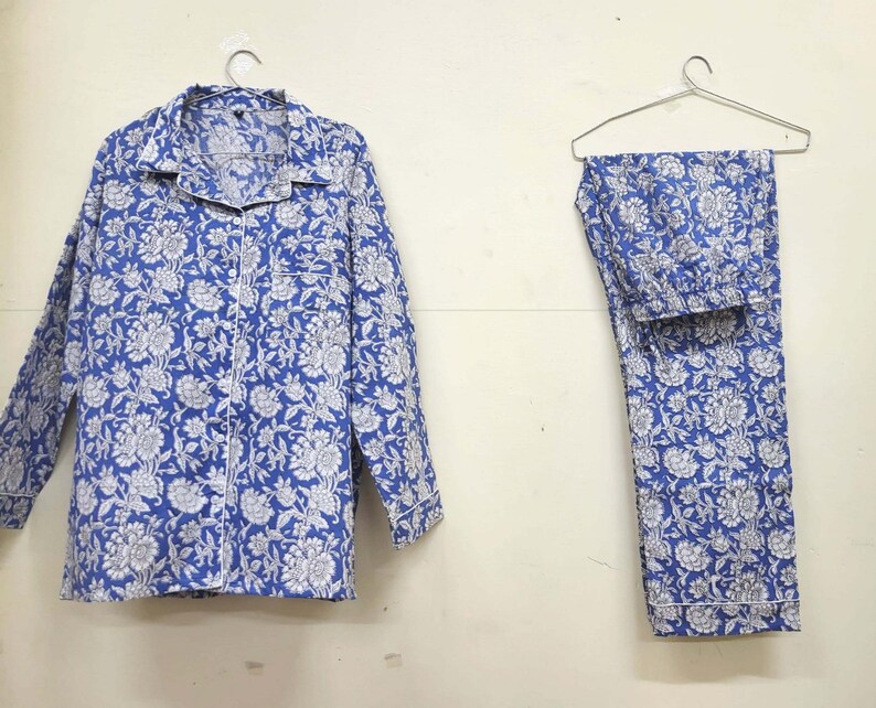 May include: A blue and white floral print pajama set with long sleeves and pants. The set is made of cotton and has a button-up top.