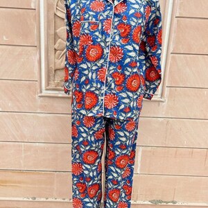 May include: Blue and red floral print pajama set with white piping. The top has a button-up front and long sleeves. The pants have a straight leg.