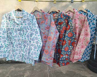 以下が含まれることがあります： 異なる花柄のロングスリーブシャツが5枚。シャツは白地に青、ピンク、赤、ターコイズブルーの花柄プリント。シャツは物干し竿にかけられている。
