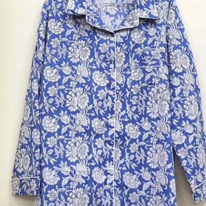 May include: A blue and white floral print long-sleeved shirt with a white trim around the collar and cuffs. The shirt has a button-up front.