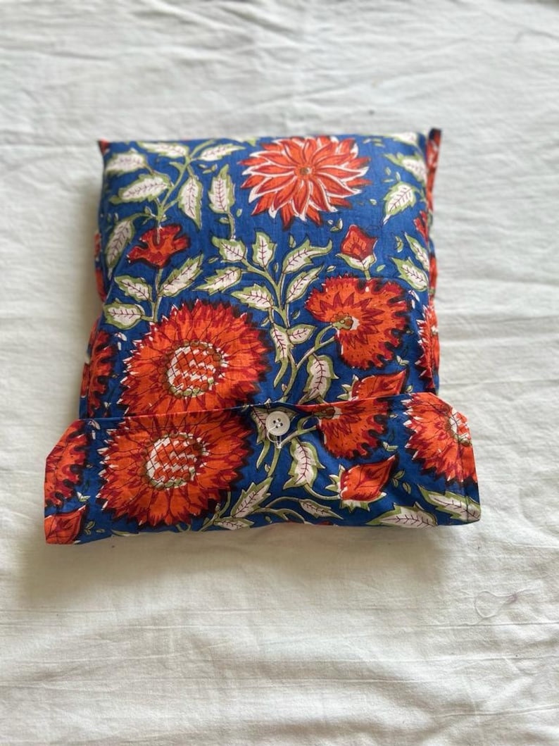 May include: A blue and orange floral patterned pillow with a white button closure.