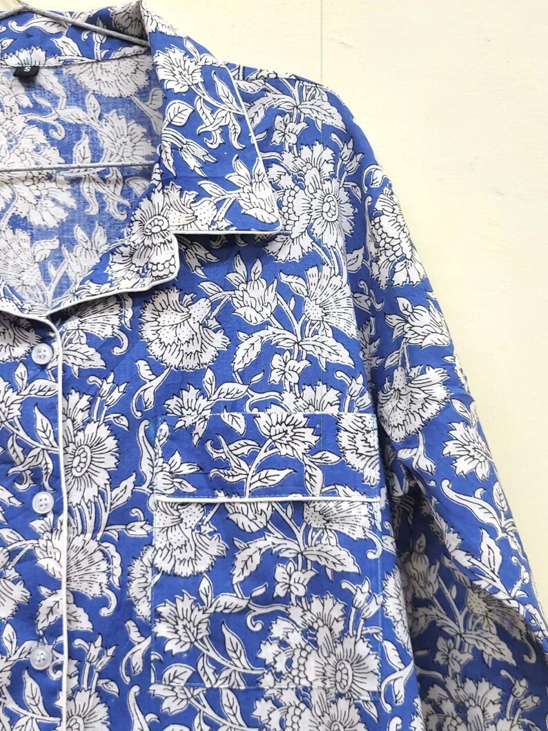 May include: A blue and white cotton shirt with a floral print. The shirt has a collar, long sleeves, and a button-up front.