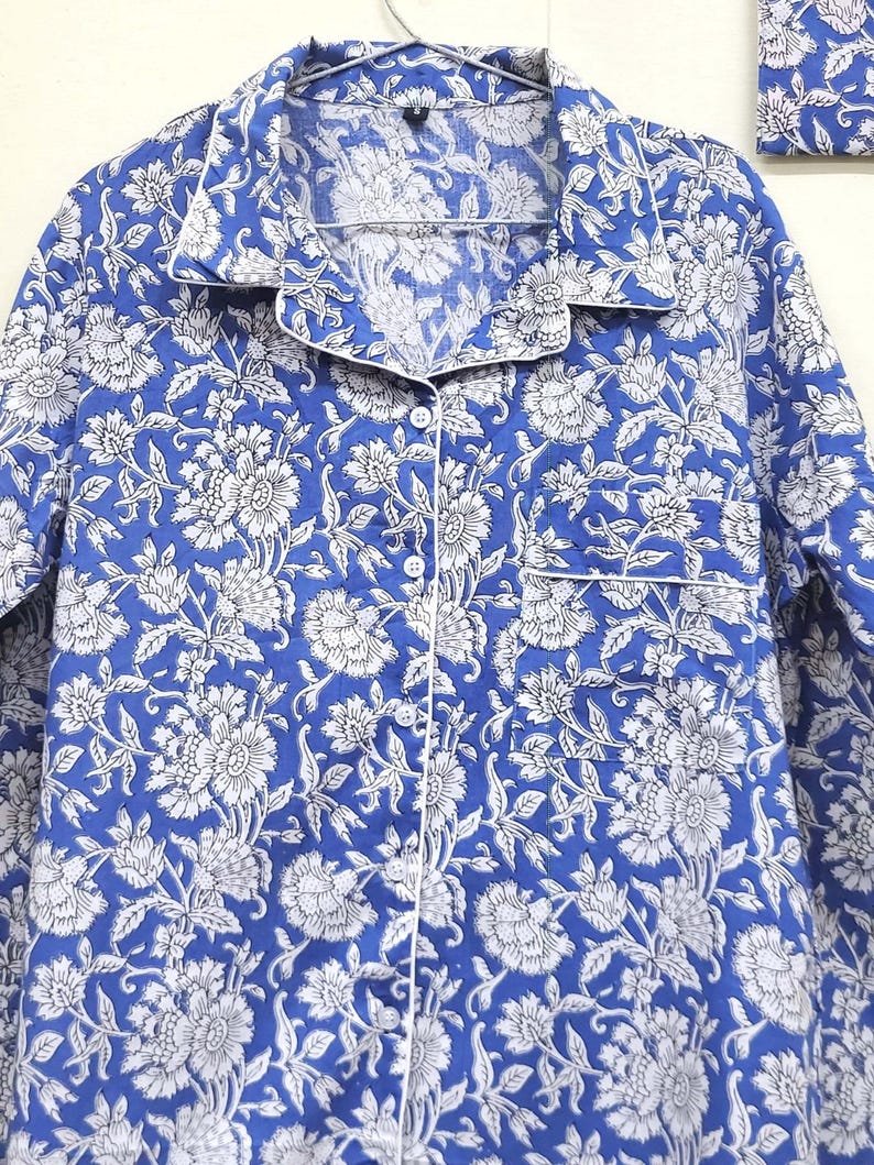 May include: A blue and white floral print pajama top with a button-up front and a white trim.