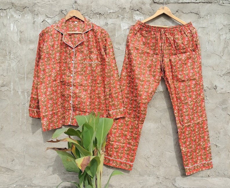 K&ouml;nnte beinhalten: Ein Pyjama-Set mit rotem und gr&uuml;nem Blumendruck, langen &Auml;rmeln und einer Hose. Der Pyjama hat einen wei&szlig;en Saum.