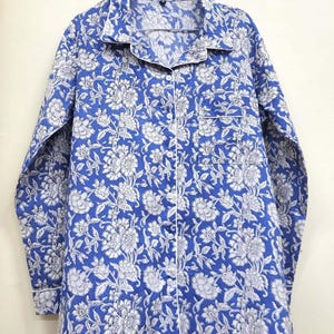 May include: A blue and white floral print long-sleeved shirt with a button-up front and a white trim.