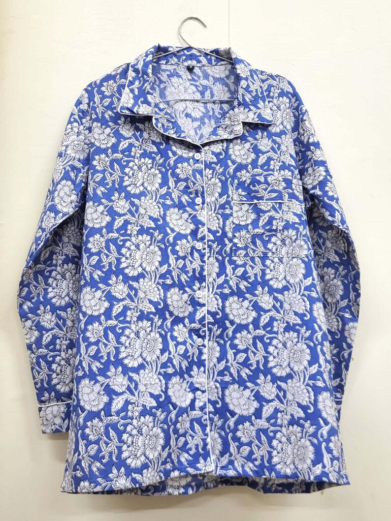 May include: A blue and white floral print long-sleeved shirt with a button-up front and a white trim.