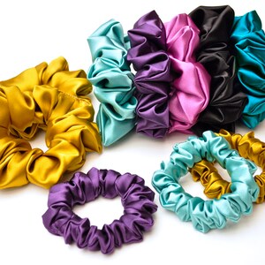 May include: A set of colorful satin scrunchies in various shades of teal, purple, pink, gold, and black. The scrunchies are made of soft, silky fabric and are perfect for holding hair in place.