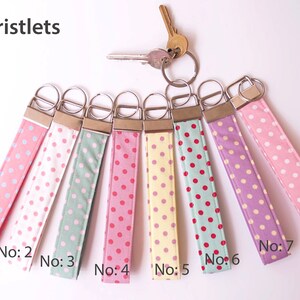 May include: Eight wristlets with different polka dot patterns. The wristlets are made of fabric and have a metal key ring. The wristlets are numbered 1 through 8.