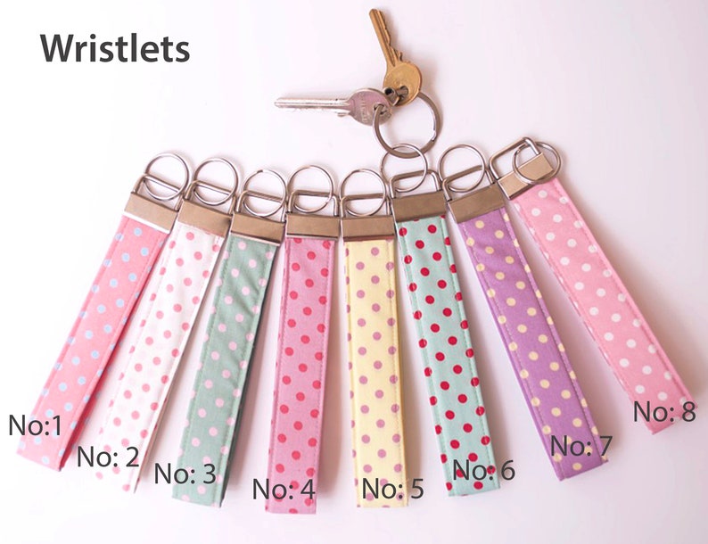 May include: Eight wristlets with different polka dot patterns. The wristlets are made of fabric and have a metal key ring. The wristlets are numbered 1 through 8.