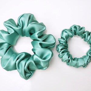 May include: Two teal blue satin scrunchies, one larger than the other.