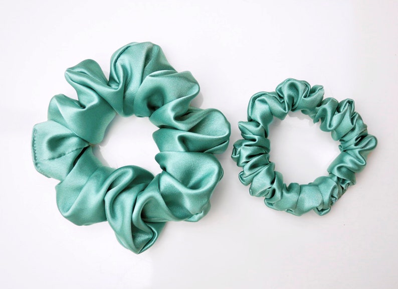 May include: Two teal blue satin scrunchies, one larger than the other.