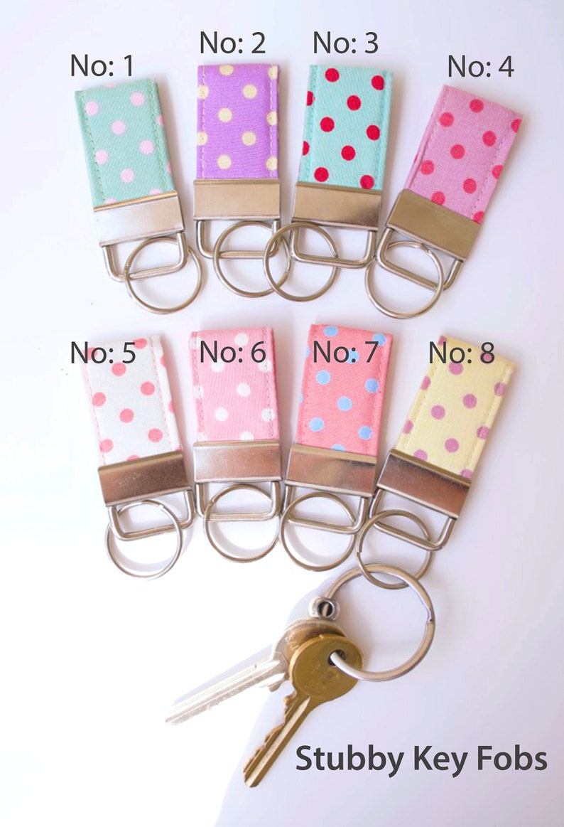 May include: Eight colorful key fobs with polka dot patterns. The key fobs are numbered 1 through 8. The key fobs are attached to silver key rings. The key fobs are on a white background. The text "Stubby Key Fobs" is at the bottom of the image.