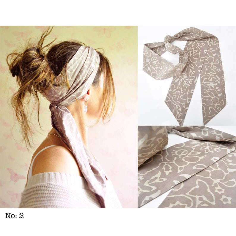 May include: A taupe-colored headscarf with a floral pattern is tied around a person's head and neck. The scarf is made of a soft fabric and has a long, flowing design. The image also shows a close-up of the scarf.