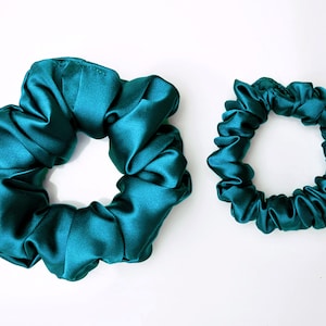 May include: Two teal blue satin scrunchies, one large and one small.