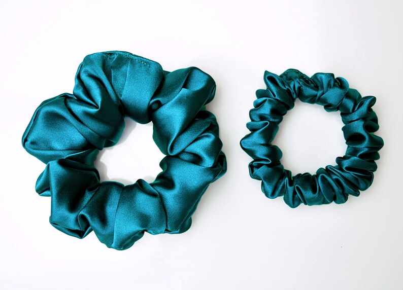 May include: Two teal blue satin scrunchies, one large and one small.