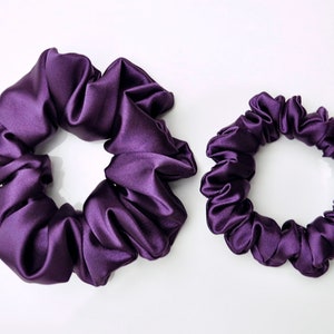 May include: Two purple satin scrunchies, one larger than the other.