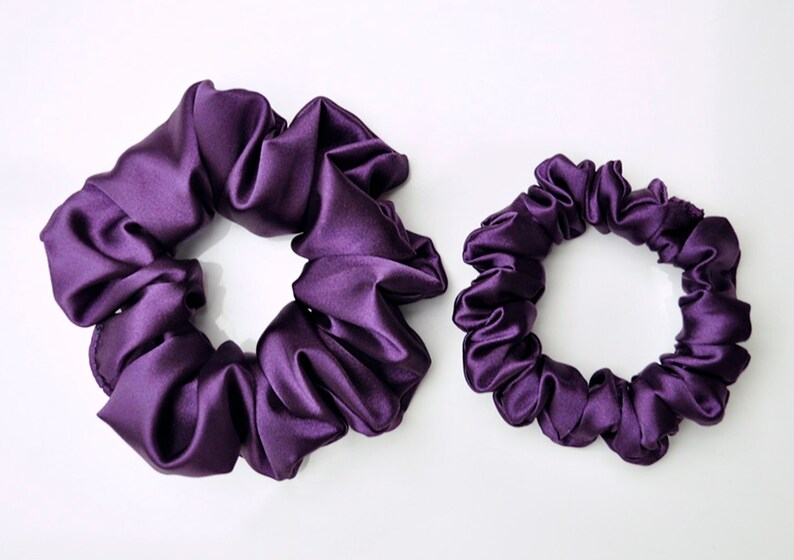 May include: Two purple satin scrunchies, one larger than the other.