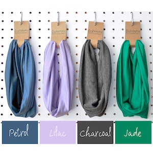 May include: Four fabric headbands in petrol blue, lilac, charcoal grey, and jade green, displayed on a pegboard. Each headband has a brown tag with the text "Scrummy Scrunchies". Below each headband is a colour-matched label with the colour name.