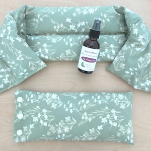 May include: A set of spa products, including a neck wrap, a small pillow, and a spray bottle. The items are light green with a white floral pattern. The spray bottle has a label that reads "My Happy Mist".
