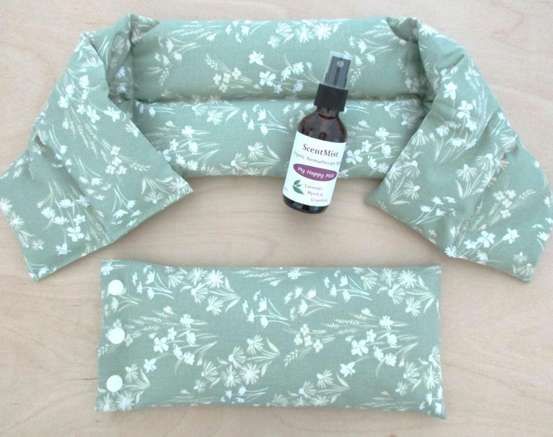 May include: A set of spa products, including a neck wrap, a small pillow, and a spray bottle. The items are light green with a white floral pattern. The spray bottle has a label that reads "My Happy Mist".