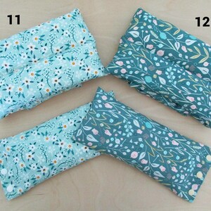 May include: Four rectangular fabric items with floral patterns. Two are light blue with white flowers, and two are teal with white, pink, and yellow floral designs. The items are arranged on a light wood surface. Numbers 11 and 12 are visible.