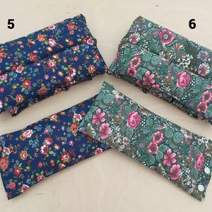May include: Several rectangular, floral-patterned pillows in shades of blue and green. The pillows feature a variety of colorful flowers. Some pillows have button closures. The pillows are likely for relaxation or therapeutic use.