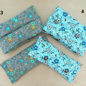 May include: Four rectangular fabric items, two in gray with teal and yellow floral patterns, and two in light blue with white and brown floral patterns. The items appear to be small pillows or pouches.