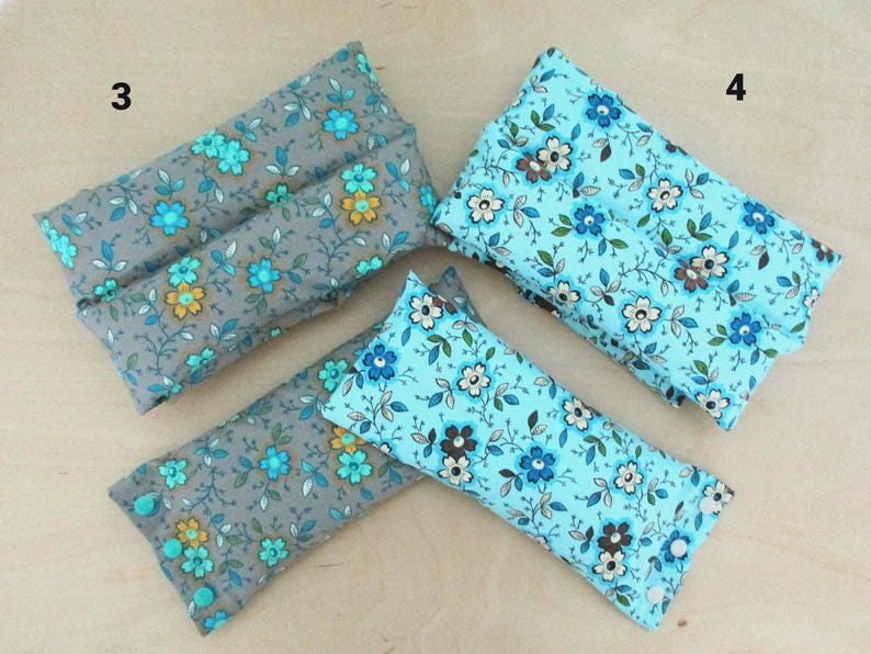May include: Four rectangular fabric items, two in gray with teal and yellow floral patterns, and two in light blue with white and brown floral patterns. The items appear to be small pillows or pouches.