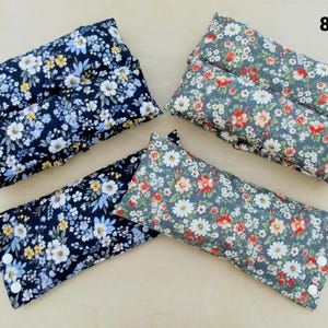 May include: Rectangular floral print pillows in navy blue and gray. The navy pillows feature white, yellow, and blue flowers. The gray pillows have red, white, and pink flowers. Each pillow has a button closure on one end.