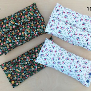 May include: Four rectangular fabric items with floral patterns. Two are black with colorful flowers, one has yellow buttons. The other two are white with pink and blue flowers, one has blue buttons. The items are likely pillows or cushions.