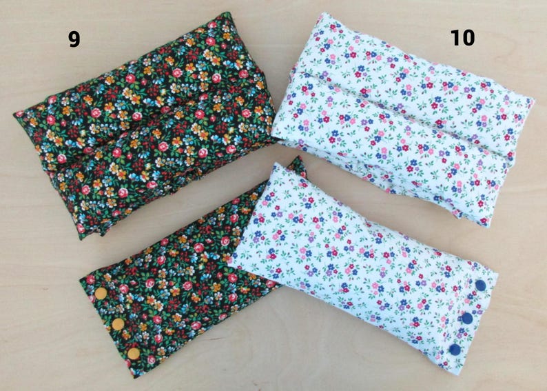 May include: Four rectangular fabric items with floral patterns. Two are black with colorful flowers, one has yellow buttons. The other two are white with pink and blue flowers, one has blue buttons. The items are likely pillows or cushions.