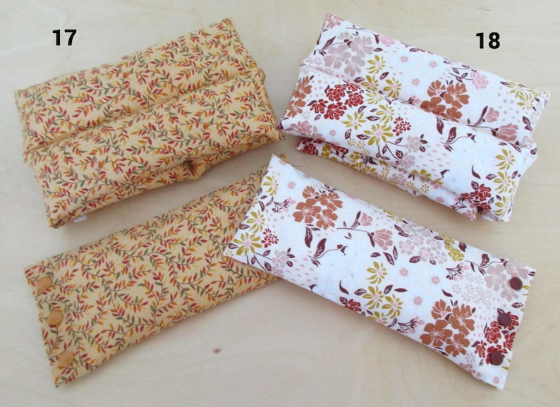 May include: Four rectangular fabric items with floral and leaf patterns. Two are yellow with red and green leaves, and two are white with red, brown, and yellow flowers. One yellow item has buttons.