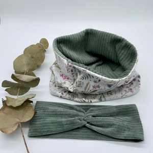 May include: A green corduroy headband and a white fabric neck warmer with a floral print. The neck warmer is reversible and has a green corduroy lining.
