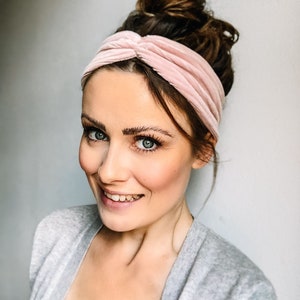 May include: A woman with a pink velvet headband in her hair, wearing a grey cardigan and a lace top.