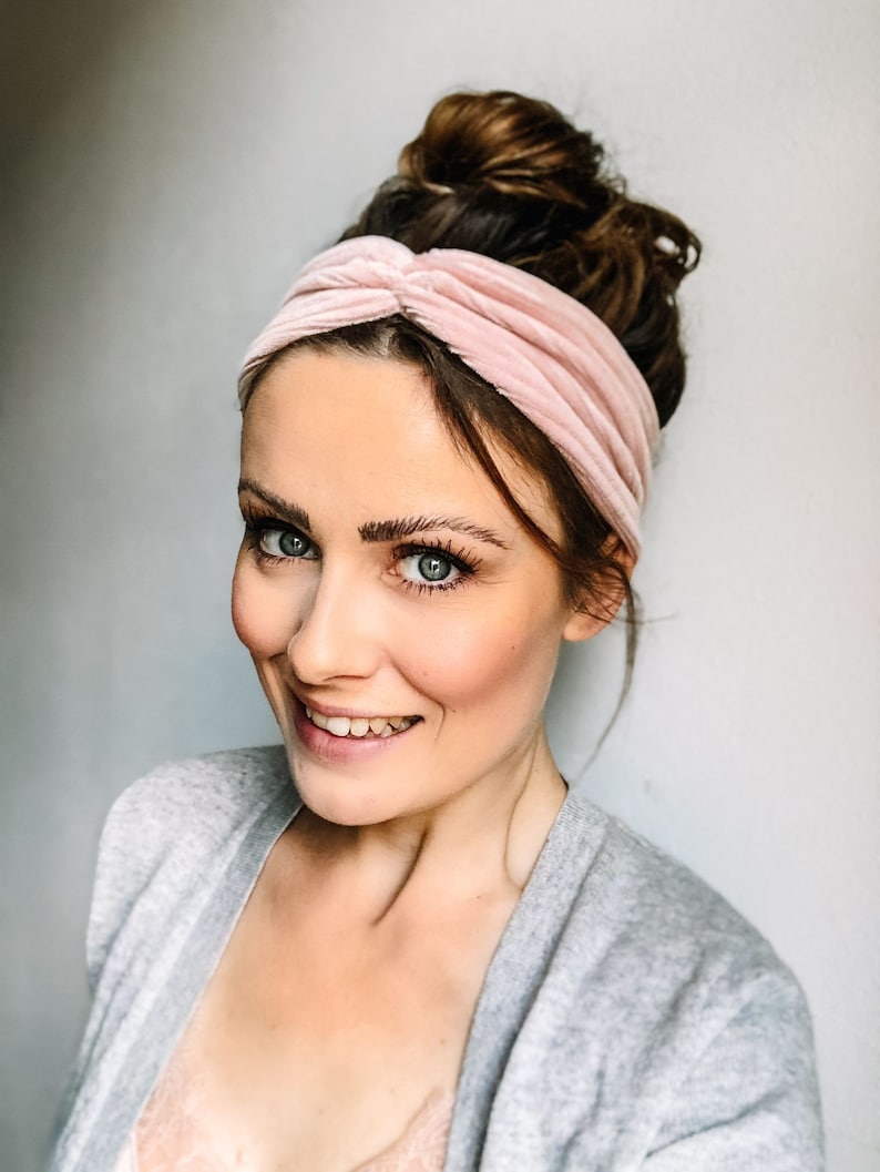 May include: A woman with a pink velvet headband in her hair, wearing a grey cardigan and a lace top.