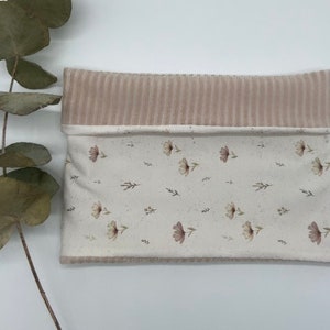 Puede incluir: Una pequeña bolsa rectangular con la parte superior de pana beige y la parte inferior blanca con un estampado floral. La bolsa está hecha de tela suave y tiene un toque rústico sutil.