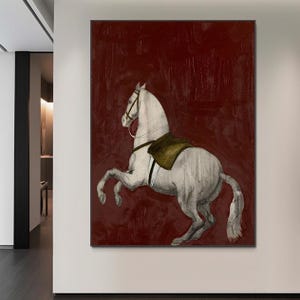 May include: A framed canvas art print featuring a white horse rearing up against a deep red background. The horse has a saddle and bridle, and the artwork has a vintage, textured appearance. The artwork is displayed on a white wall.